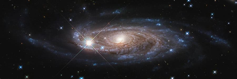 Bright spiral galaxy with glowing core and extended spiral arms filled with stars.